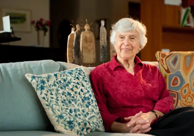 Woman in red shirt sitting on sofa, looking at camera